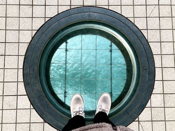 Low section of person standing by swimming pool