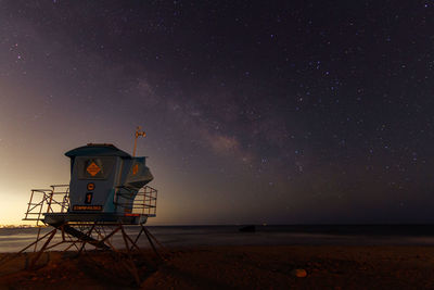 Lifeguard hut on beach against sky at night