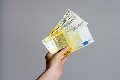 Close-up of hand holding paper against white background