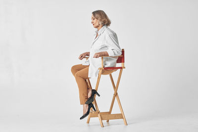 Man sitting on chair against white background