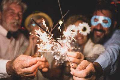 Midsection of man holding sparkler at night