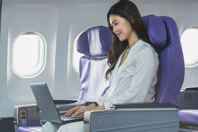 Woman using laptop while sitting in airplane