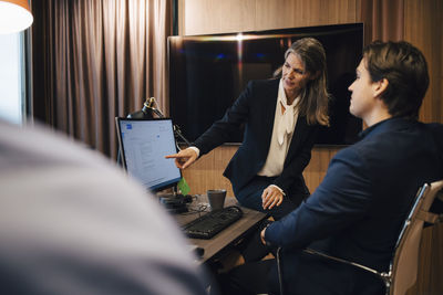 Female lawyer discussing over computer with male colleague at office