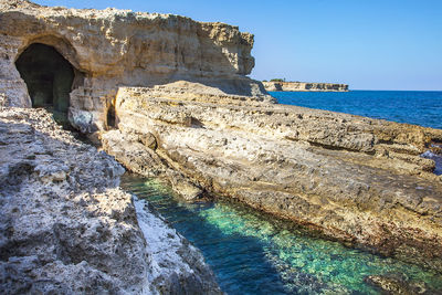 Rock formations by sea against sky