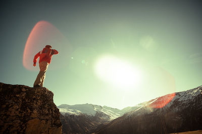 Low angle view of person standing on rock against sky