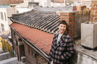 Portrait of smiling young woman standing on roof