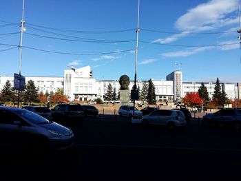 Cars on city street against blue sky