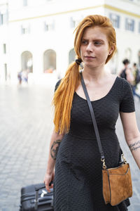 Young woman with suitcase walking in city