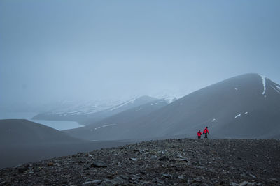 People on snowcapped mountain against sky