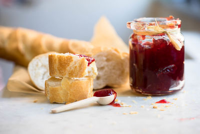 Baguette and strawberry jam on table