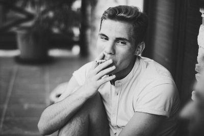 Young man smoking while sitting at entrance