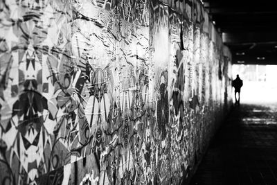 Rear view of man walking against graffiti wall