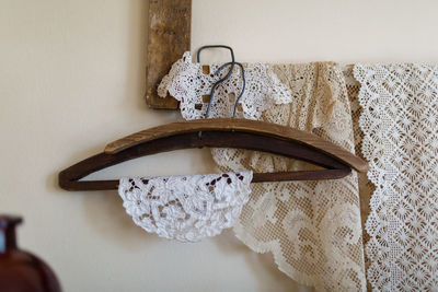 Close-up of lace hanging on coathanger by wall