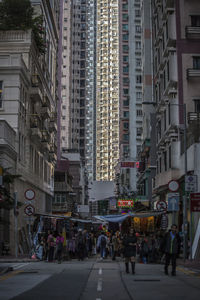 People walking on city street amidst buildings