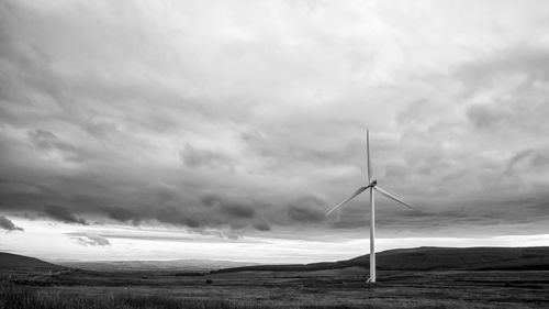 Wind turbines on field against sky