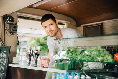 Portrait of male owner standing in food truck