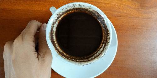 Directly above shot of hand holding black coffee