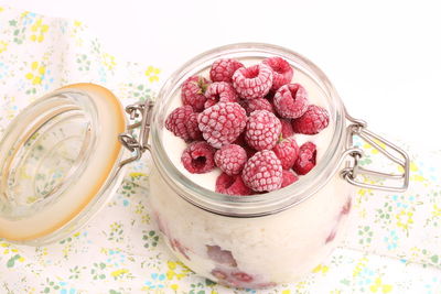 Breakfast rice porridge with vanilla sauce, frozen raspberries in a glass jar white background