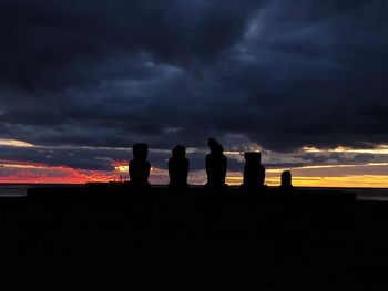 Silhouette of people against dramatic sky during sunset