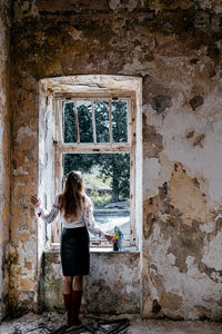 Rear view of woman standing against wall