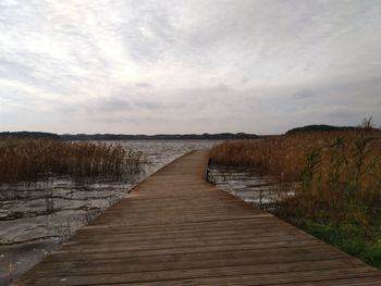 Boardwalk leading towards sea against sky
