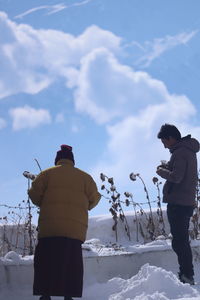 Rear view of man standing on snow against sky