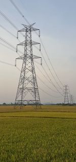 Low angle view of electricity pylon on field against sky