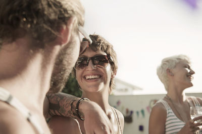 Smiling woman looking at man while standing by friend during party