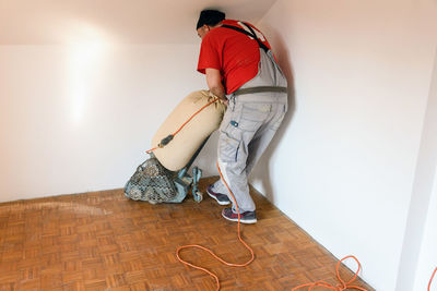 Man sanding hardwood floor with grinding machine
