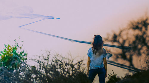 Rear view of woman standing against sky during sunset