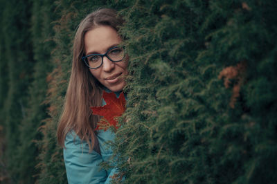 Portrait of young woman standing against plants