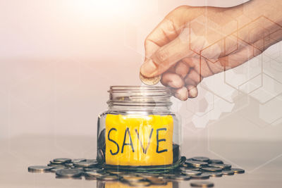Close-up of hand holding glass jar on table