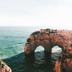 Rock formation in sea against clear sky