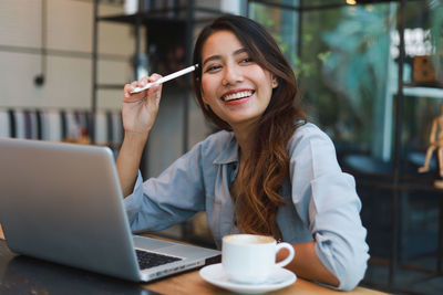 Portrait of a smiling young woman using laptop