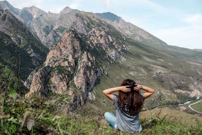 Rear view of woman sitting against mountains