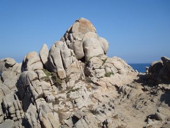 Rock formations in sea against clear blue sky