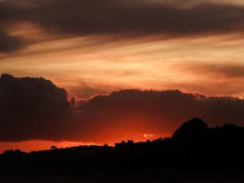 Scenic view of silhouette landscape against dramatic sky during sunset