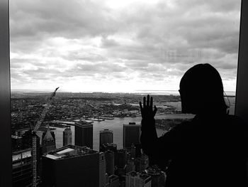 Rear view of silhouette man photographing cityscape against sky
