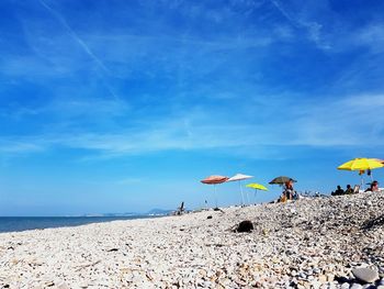 People on beach against blue sky