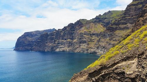 Scenic view of sea by cliff against sky