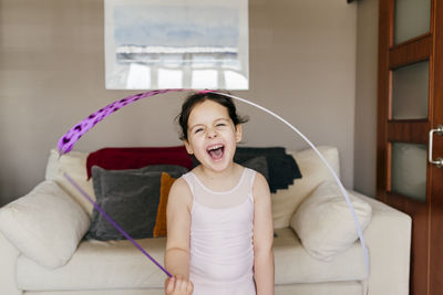 Cute happy little brunette girl with ribbon with closed eyes during rhythmic gymnastic training at home