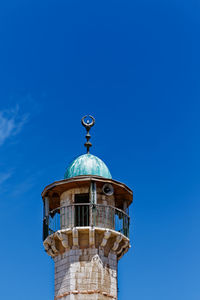 Low angle view of minaret against blue sky