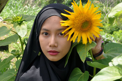 Close-up portrait of young woman with sunflower