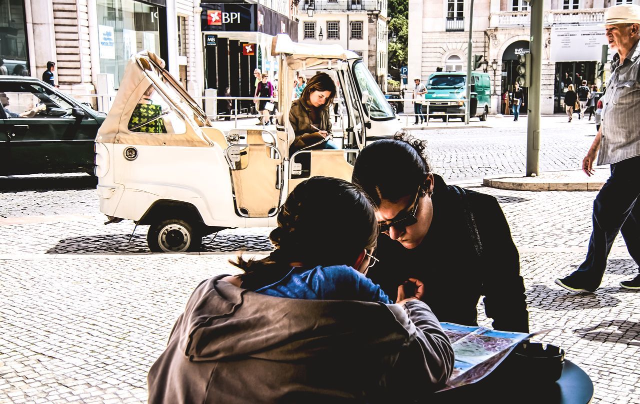 two people, togetherness, sunlight, bonding, sitting, wireless technology, care, adults only, people, connection, city, real people, adult, outdoors, young adult, day