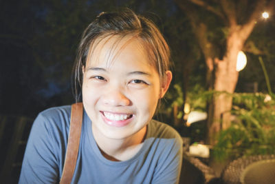 Portrait of smiling woman against illuminated trees