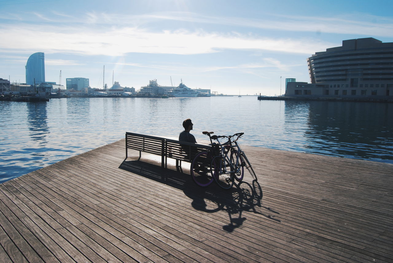 city, two people, building exterior, river, architecture, men, water, outdoors, travel, built structure, waterfront, bonding, sky, urban skyline, rear view, cloud - sky, young adult, day, togetherness, city life, adults only, real people, cityscape, women, nautical vessel, adult, people, bridge - man made structure, beauty in nature, nature, skyscraper, only men