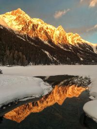 Scenic view of lake by snowcapped mountain against sky