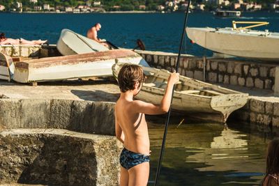 Rear view of shirtless man standing on pier