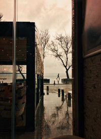 Buildings and trees against sky seen through glass window