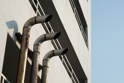 Three pipe ventilation ducts for venting smoke outside the building, rusty surface surrounding.